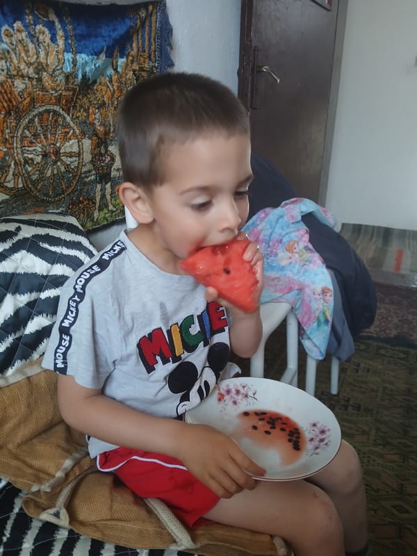 Children enjoy watermelon snack at home in Bulgarian village