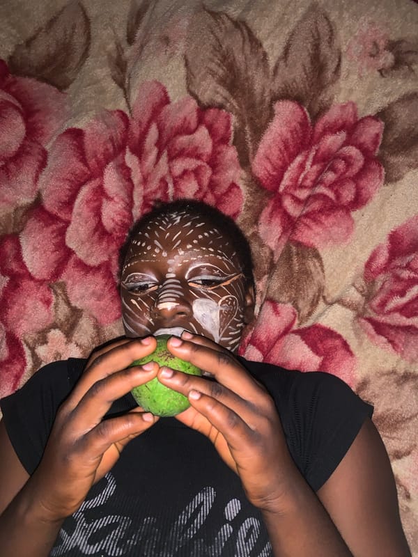 Person with white face paint rests on blanket in Nigeria