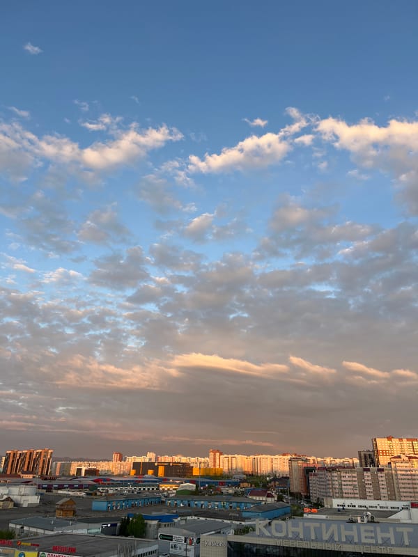 Partly cloudy evening sky observed over Krasnoyarsk cityscape