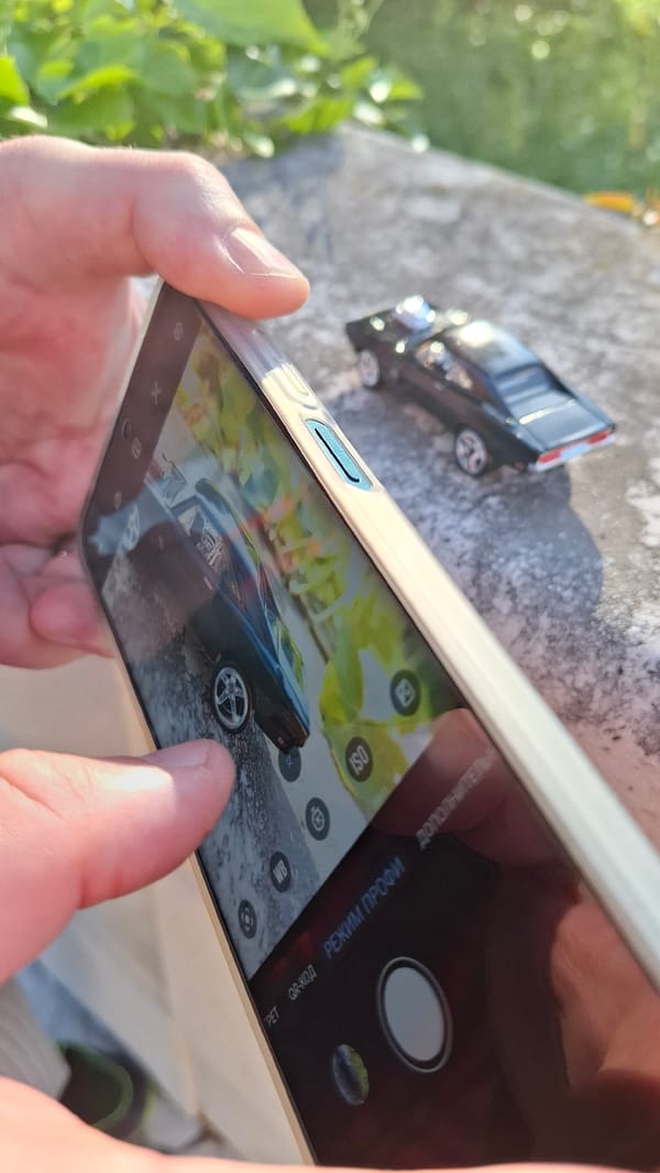 Person photographs black toy car with smartphone