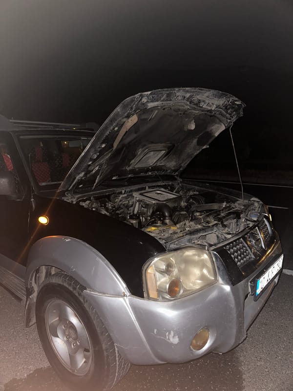 Two men repair car engine on street in Ula