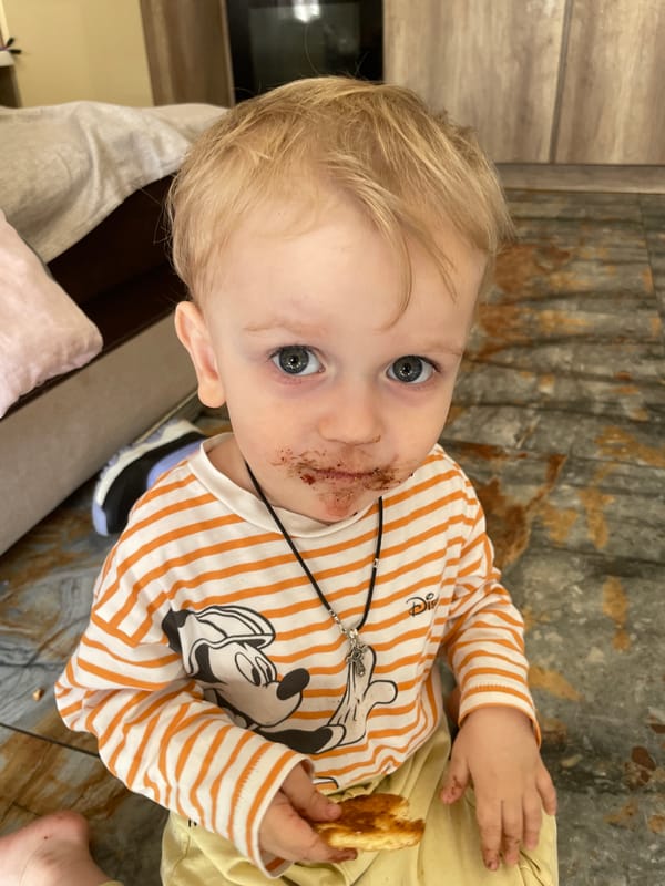Child spotted with chocolate-covered face holding toast