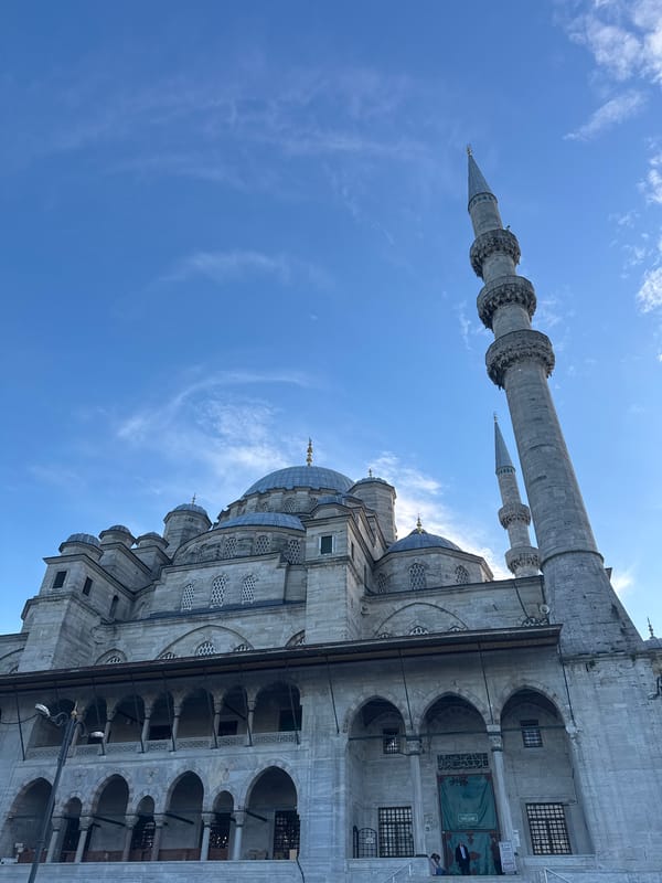 Tourist photographs historic Yeni Cami mosque in Istanbul