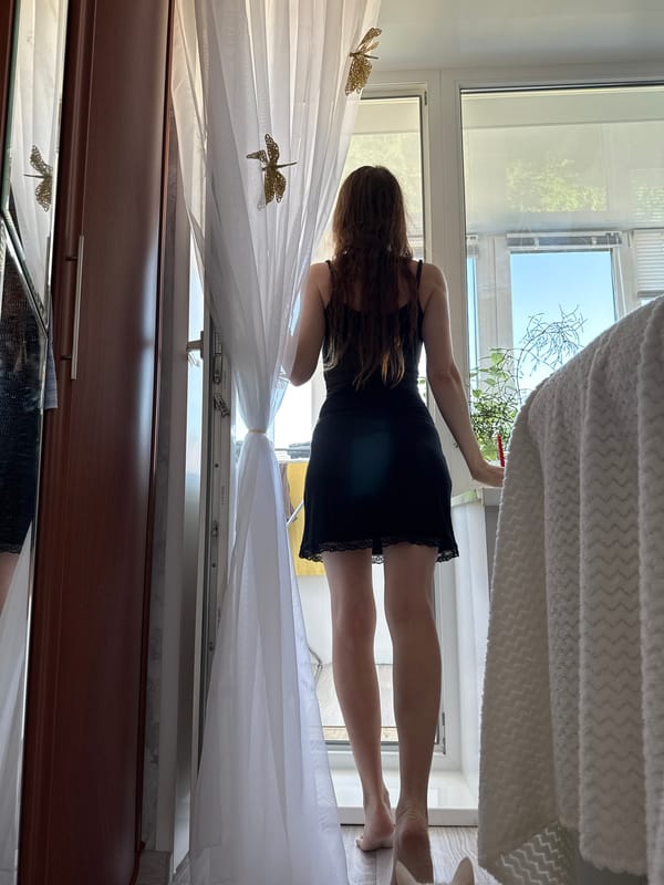 Standing by a draped window with dragonfly curtains