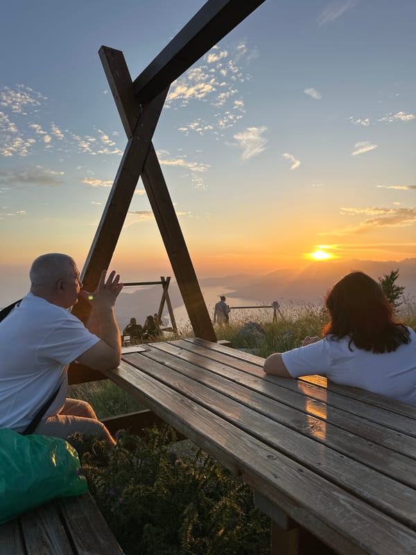 Couple watches sunset over bay from picnic table in Montenegro