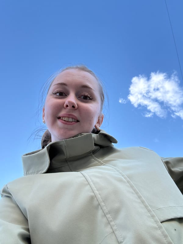Woman photographed outdoors under blue sky with urban backdrop