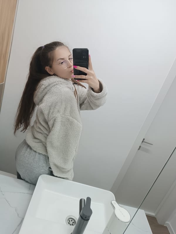 Woman takes bathroom selfie in gray outfit