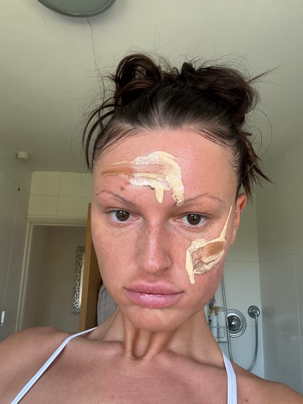 Woman applies makeup in bathroom, Wealden UK morning routine