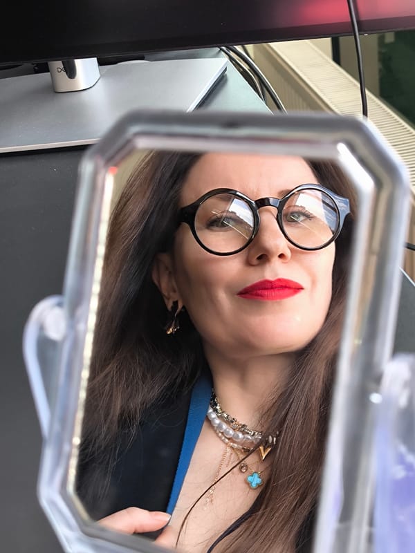 Woman with glasses reflected in tabletop mirror, Riga