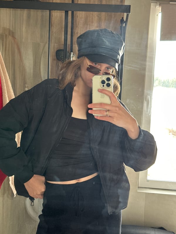 Person takes bathroom selfie with gold iPhone wearing black outfit