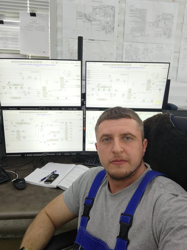 Worker monitors industrial processes from multi-screen control station