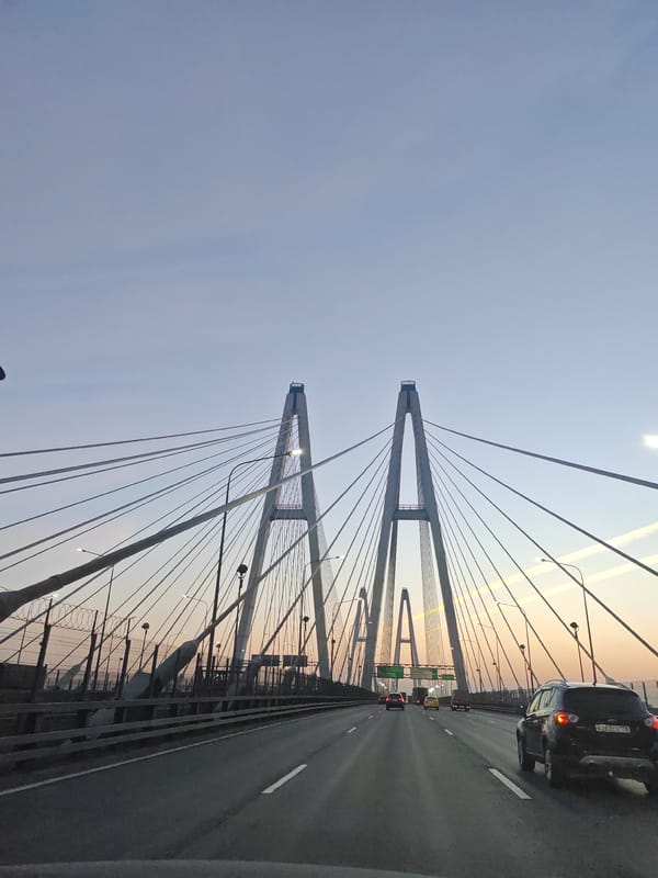 Traffic flows on highway approaching cable-stayed bridge in Novosaratovka