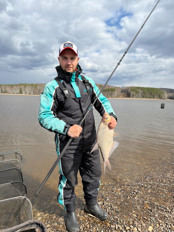 Fisherman catches large fish on rocky Chaikovsky shoreline
