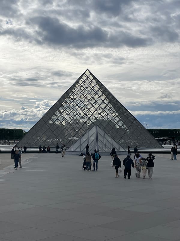 Afternoon tourist activity continues at Louvre Museum under cloudy skies