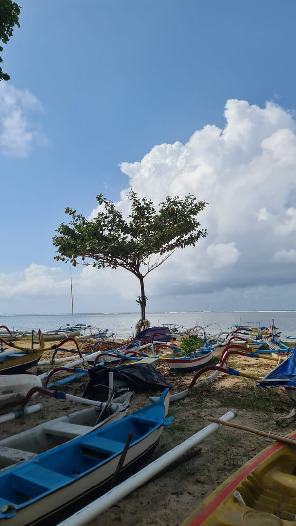 Traditional outrigger canoe on a calm Sanur Beach shoreline