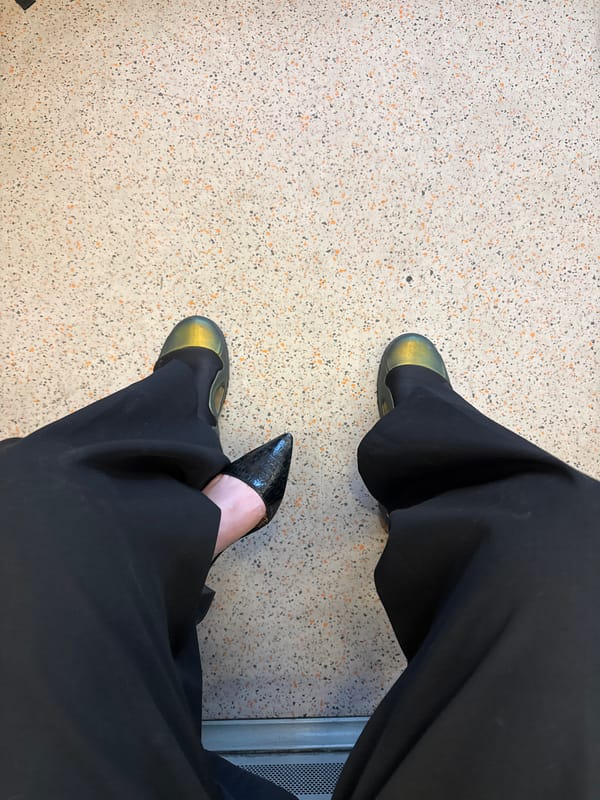 Person in black trousers seated in London public space