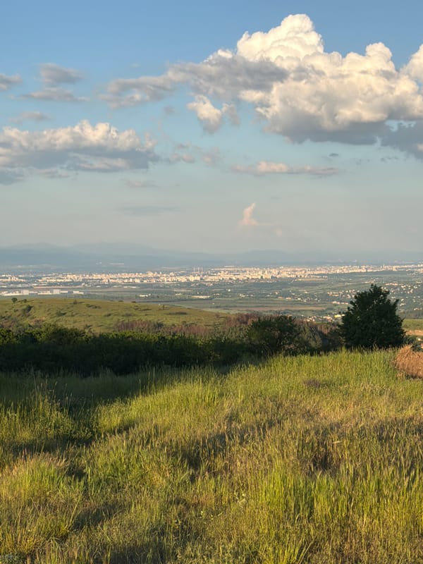 Person walks hillside path near Klisura under cloudy skies