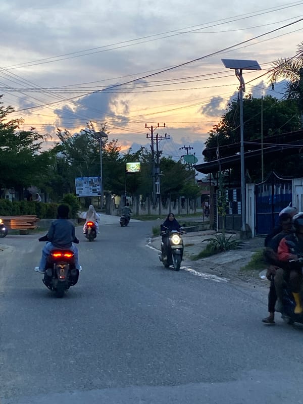 Lhokseumawe streets at dusk, motorcycles under a golden sky