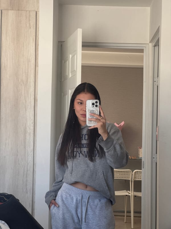 Woman takes selfies in grey sweatsuit in Ocotlán bedroom