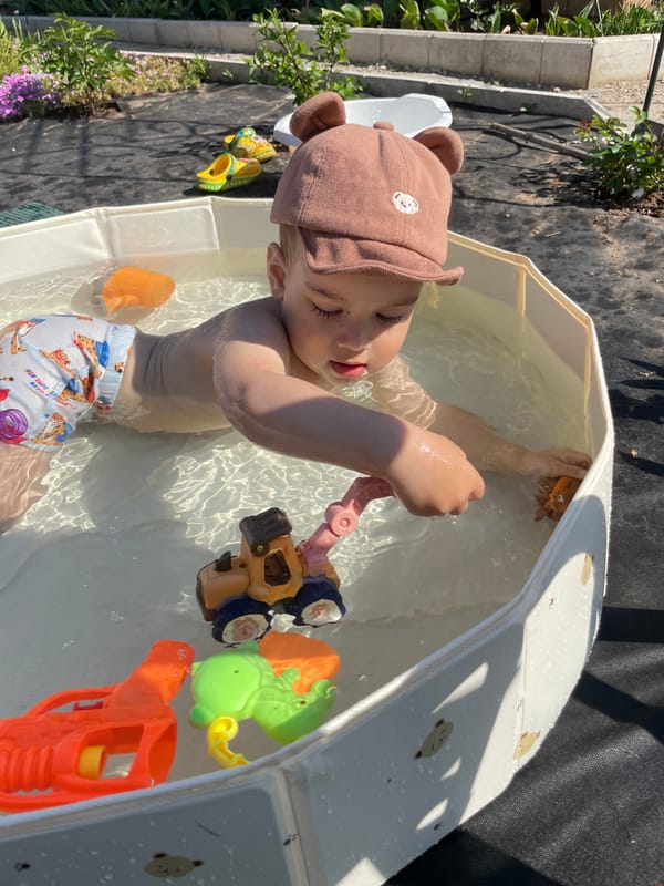 Toddler plays in backyard pool during sunny morning in Russia