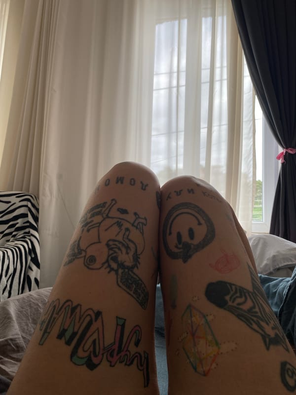 Tattooed legs at rest on a grey surface in Tbilisi