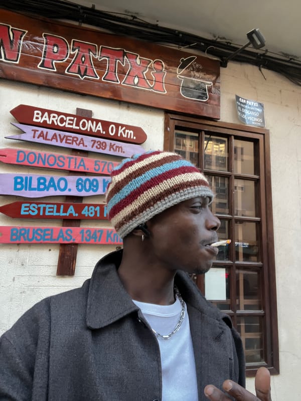 Man in striped beanie smokes near city signs in Barcelona