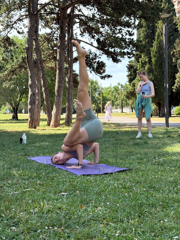 Woman practices yoga in Budva park as parasailers soar overhead