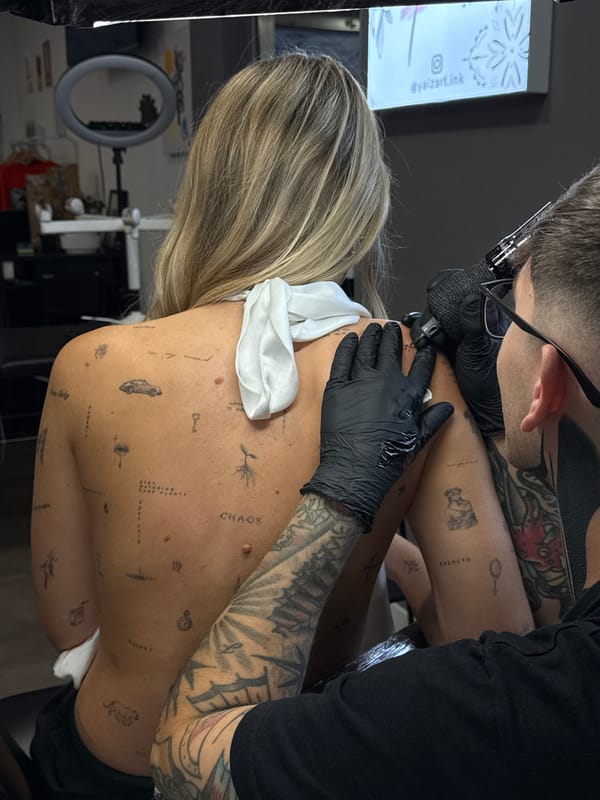 Woman receives back tattoo from artist in Yaiza, Spain