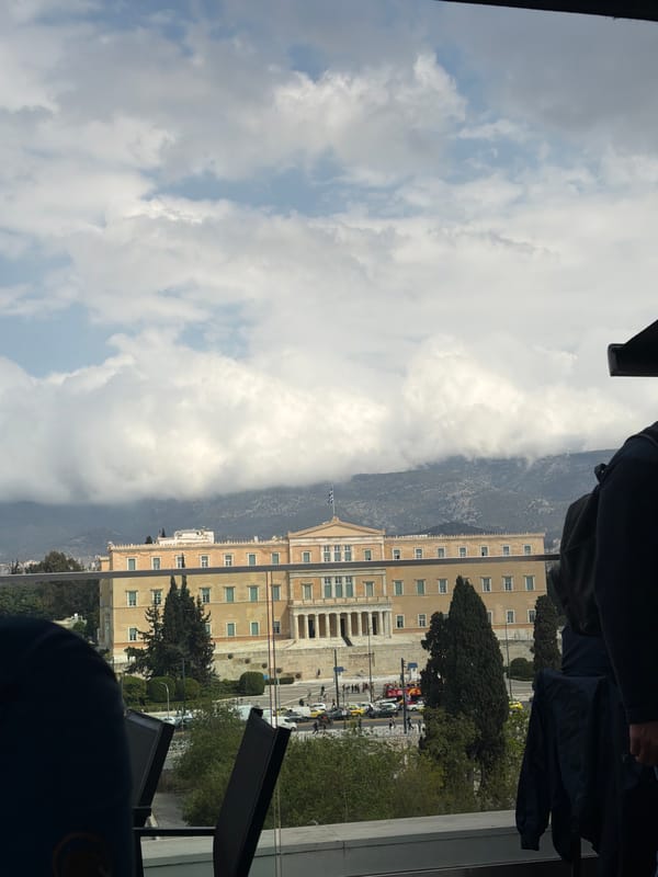 Woman takes selfies overlooking Athens Parliament from rooftop cafe