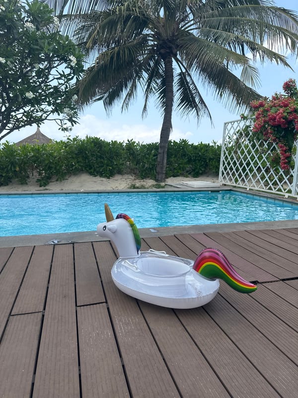Woman observes tropical pool area from indoor windows