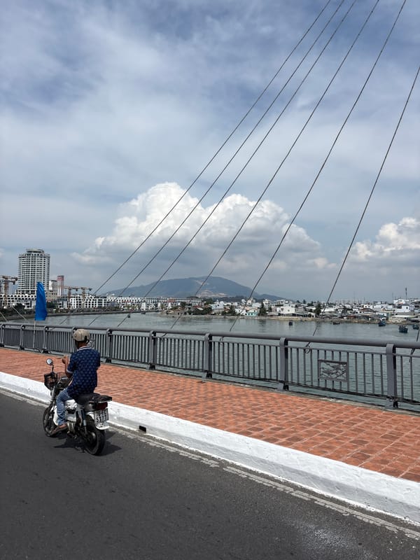 Motorcyclist crosses bridge in Nha Trang under cloudy skies