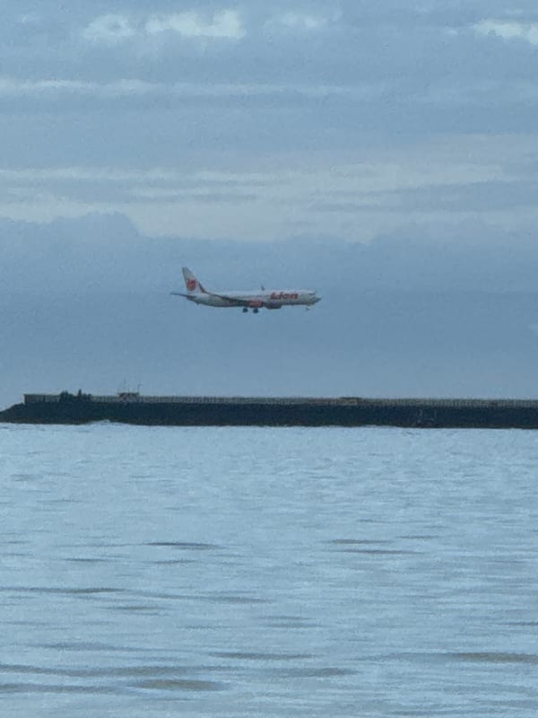 Commercial airplane lands over water near Kuta Selatan beach
