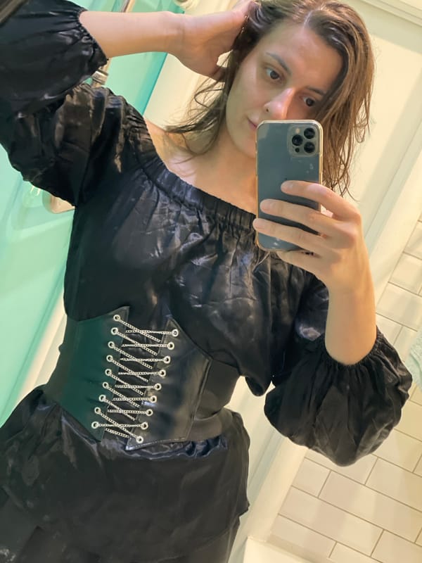 Woman takes bathroom selfie in black off-shoulder dress