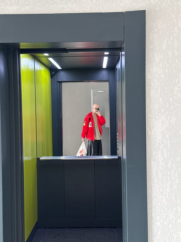 Person in red jacket photographed in elevator mirror