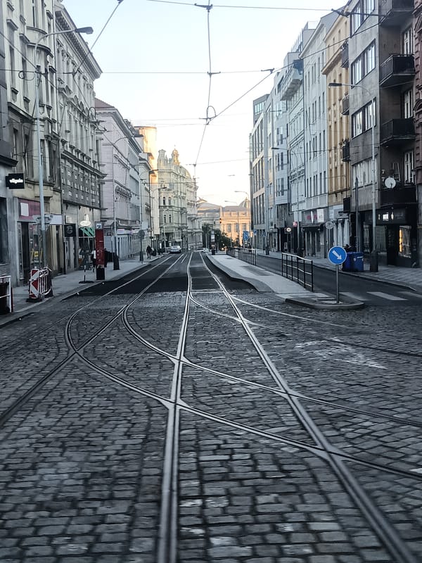 Rainy morning traffic on a cobblestone street near Prague's National Museum