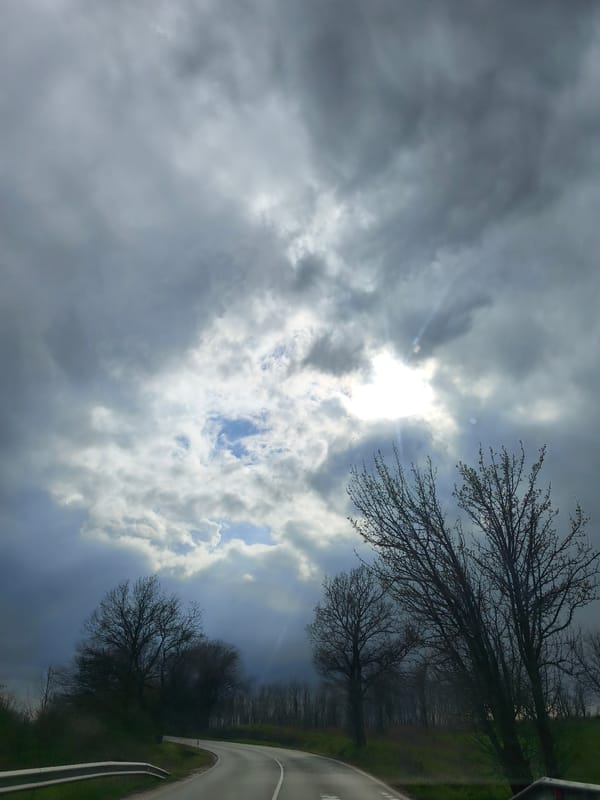 Storm clouds gather over Benkovski road with sunlight breaks