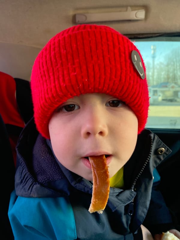 Child eats bread in car during spring drive in Chaykovsky