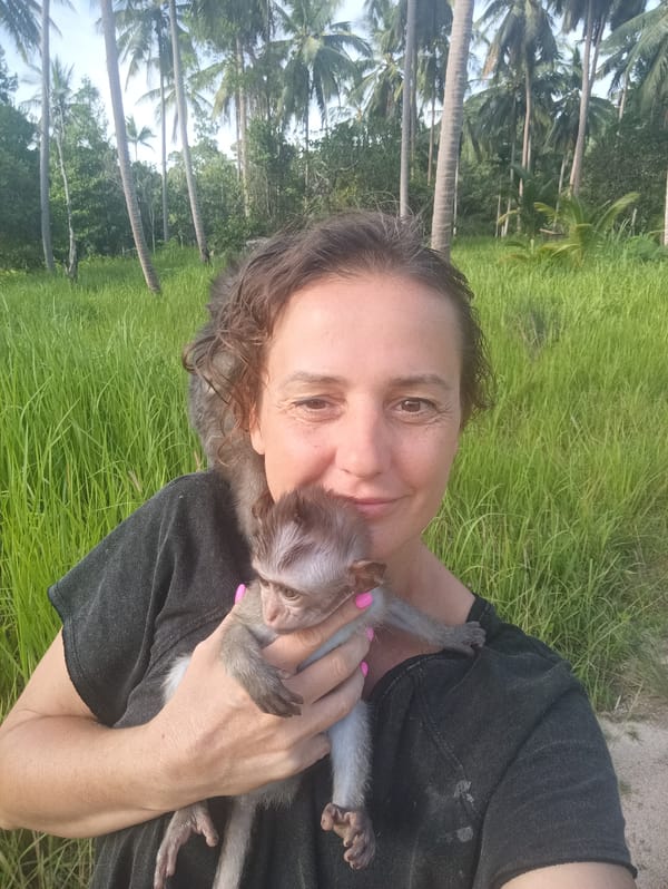 Woman poses with two monkeys in outdoor setting