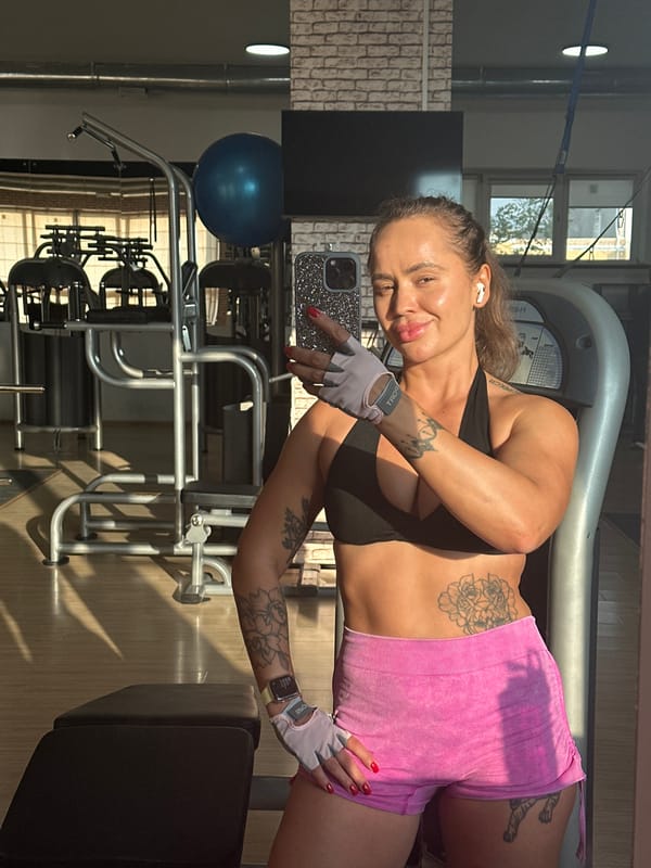 Gym selfie mid-workout, gloves and earbuds on.