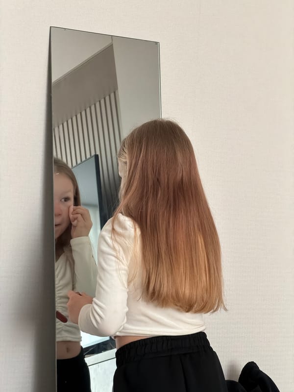 Girl touches face while looking in mirror in Markovo
