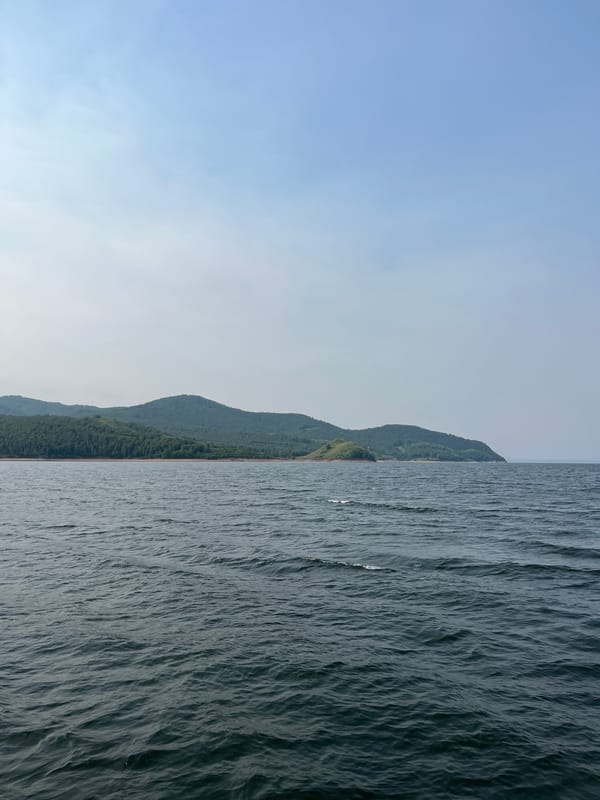 Dark water meets forested hills on a Siberian shoreline