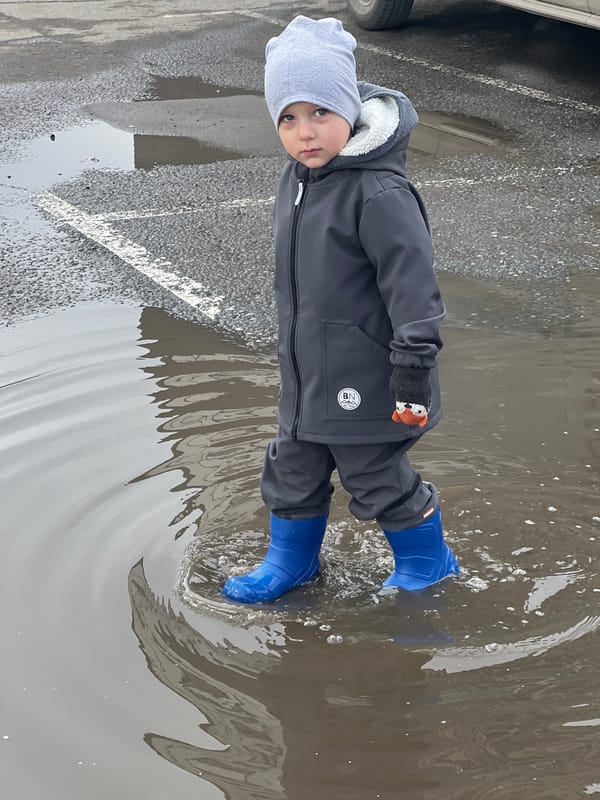 Child plays in puddles during morning outing in Mytishchi