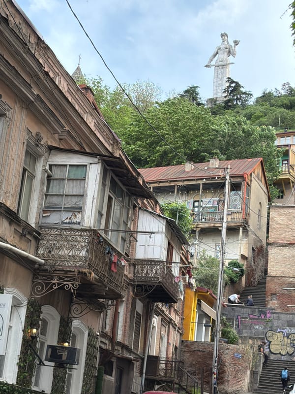 Tourist documents old Tbilisi architecture and Mother Georgia statue