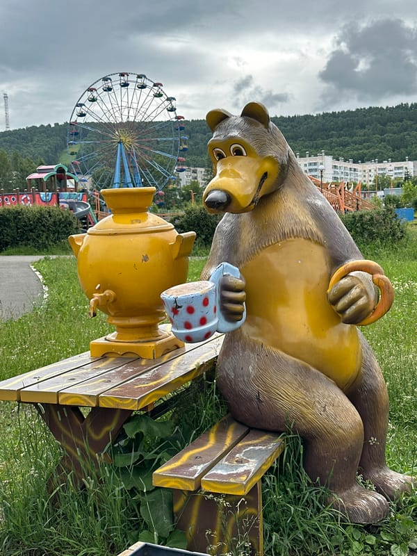 Strolling a park with fountains, flowers, bear statues, and cats