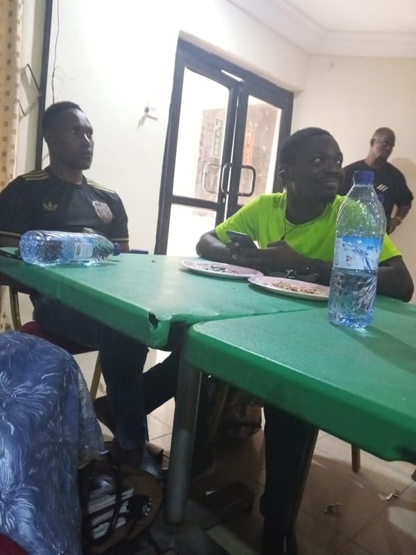 Three men gather at table with food and drinks