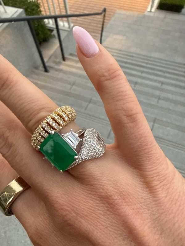 Hand displays luxury rings with emerald, diamonds in Dubai