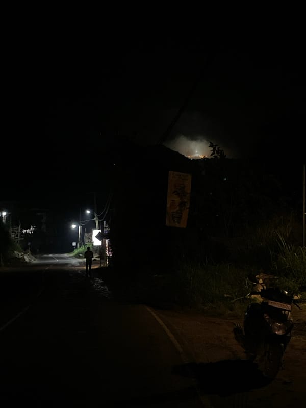 Person walks street in Kumbalwela, motorcycle parked nearby