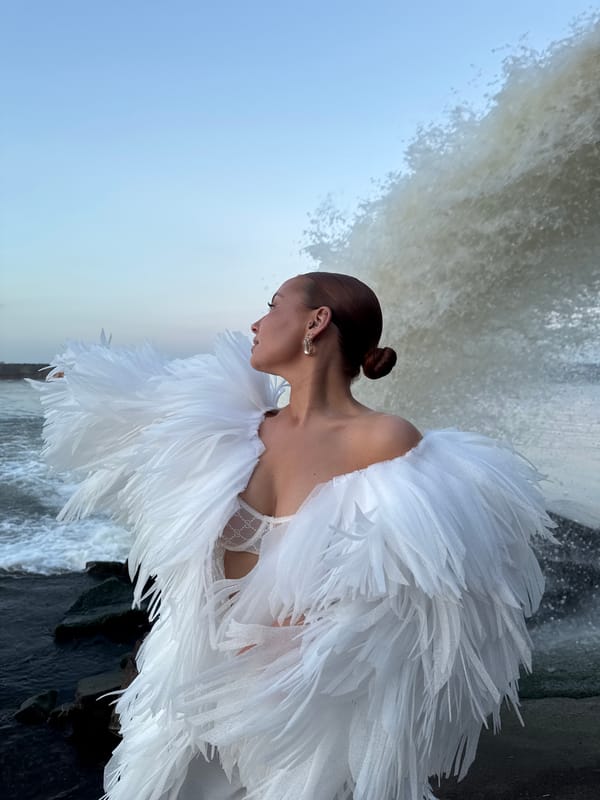 Woman in feathered dress poses by waterfall in Chaikovsky