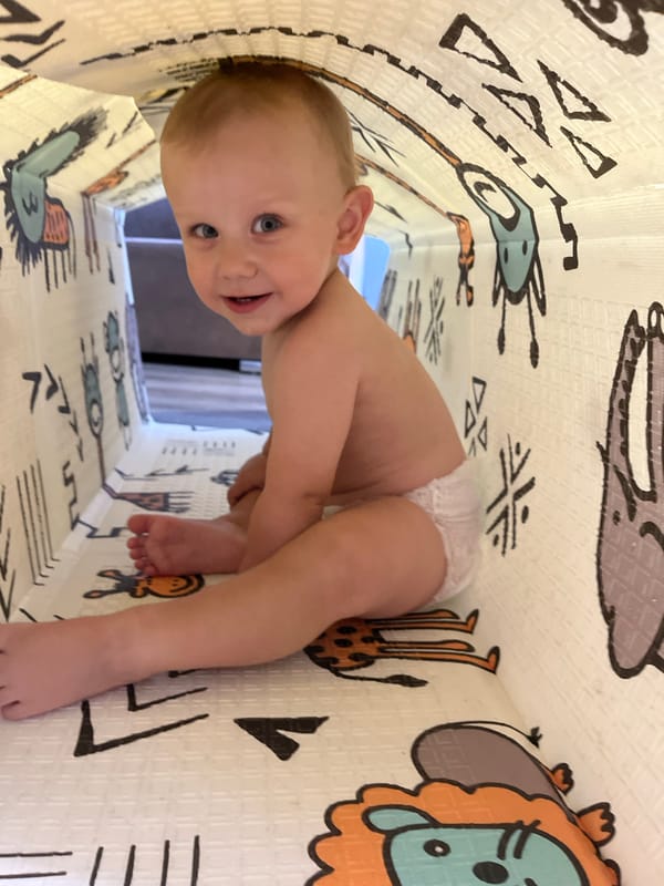 Baby explores a colorful fabric play tunnel indoors