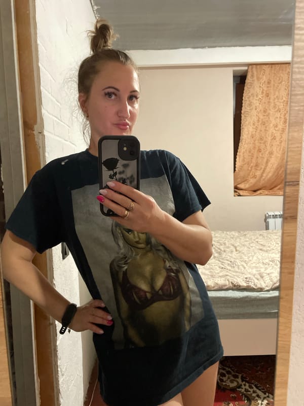 Indoor mirror selfie in Zarichne, dark graphic tee, hair up.